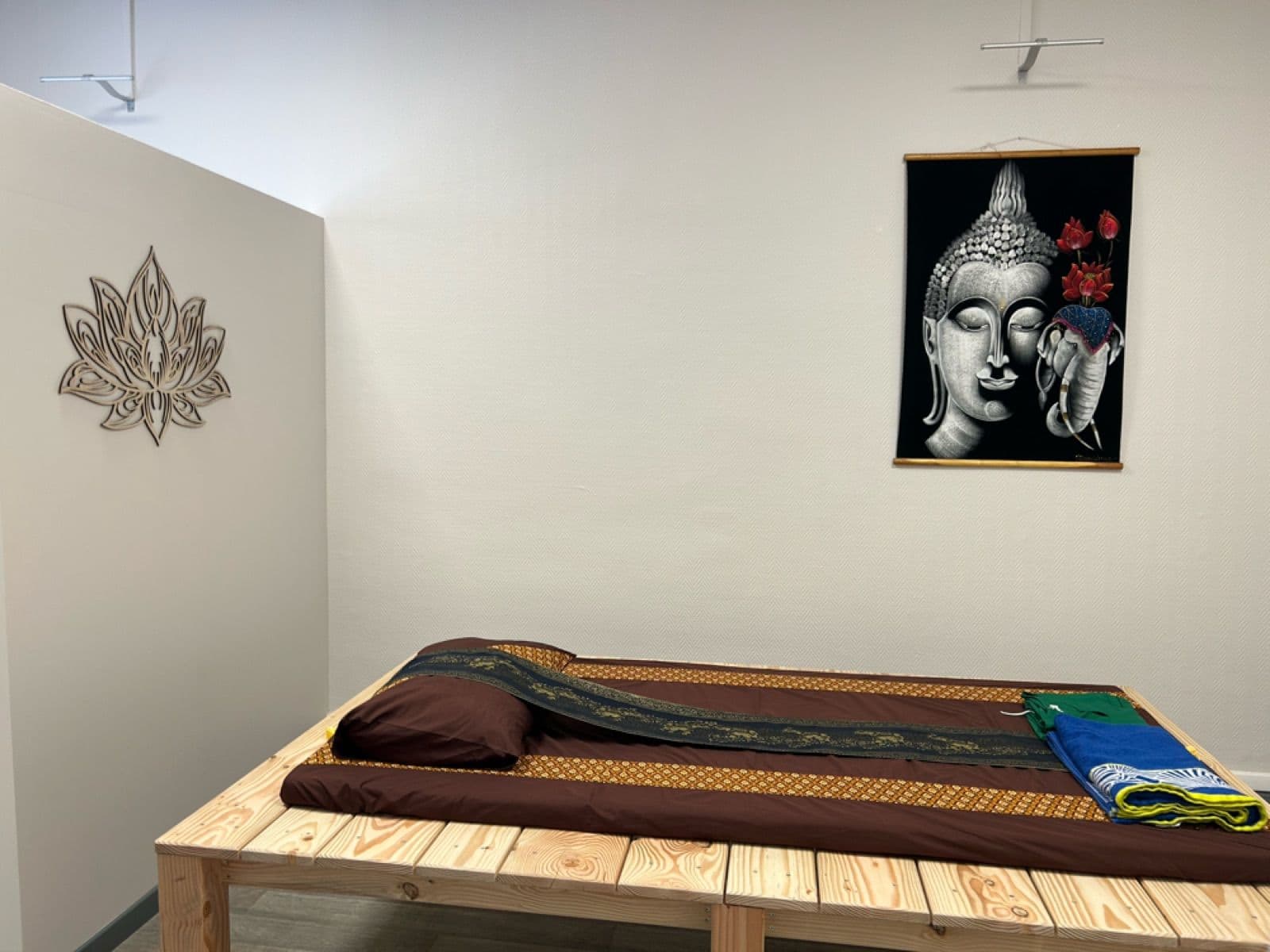 Cabine avec tapis de massage thaï traditionnel au sol et portrait de Bouddha